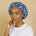 Bonnet en satin à doublure contrastée pour cheveux bouclés porté par femme, vue de profil 3/4 — détail satin