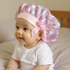 Bonnet en satin bébé motif licorne porté par bébé, vue de profil 3/4 — détail satin